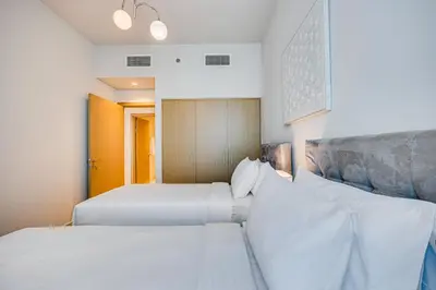 two beds in a room with white sheets and pillows at Comfy family 3BD apartment in Dubai Creek Harbour in Dubai