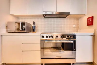 a kitchen with white cabinets and a stainless steel oven at Comfy family 3BD apartment in Dubai Creek Harbour in Dubai