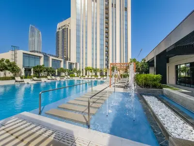 a swimming pool with a fountain in front of a building at Comfy family 3BD apartment in Dubai Creek Harbour in Dubai
