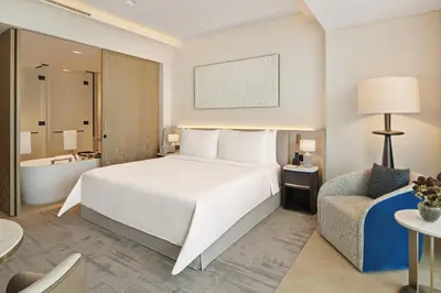 a bedroom with a large white bed and a chair at Palace Dubai Creek Harbour in Dubai