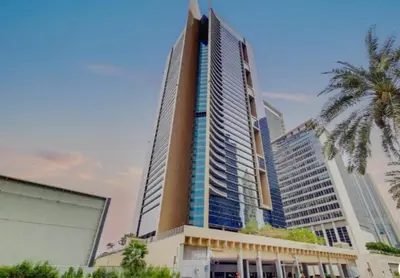 a tall building with a palm tree in front of it at Nasma Luxury Stays - Elegant 1BR With Stunning View of Park Avenue in Dubai