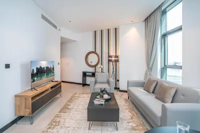 a living room with a couch and a tv at Pristine 1 Bedroom - Business Bay in Dubai