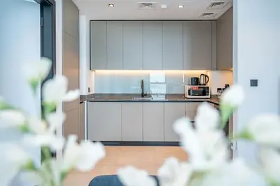 a kitchen with white cabinets and a counter top at Pristine 1 Bedroom - Business Bay in Dubai
