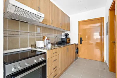 a kitchen with wooden cabinets and a stove top oven at Silkhaus New Studio in ASB Tower Walking distance to mall in Dubai