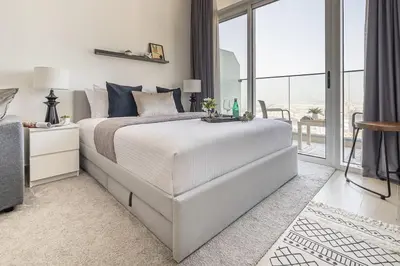 a white bedroom with a large bed and a balcony at Frank Porter - Bloom Heights in Dubai