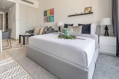 a bedroom with a large white bed and a living room at Frank Porter - Bloom Heights in Dubai