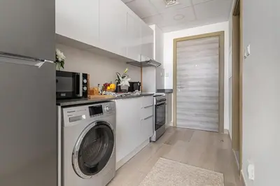a kitchen with a washing machine and a microwave at Frank Porter - Bloom Heights in Dubai