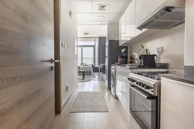 a kitchen with a stove and a hallway with a door at Frank Porter - Bloom Heights in Dubai