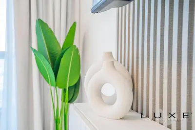 two white vases sitting on a table with a plant at Luxe - Relax in Style Scandi 1BR with Sofa Bed in Dubai