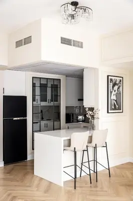 a white kitchen with a black refrigerator and white chairs at Luxury 1 bedroom with beautiful marina view! in Dubai