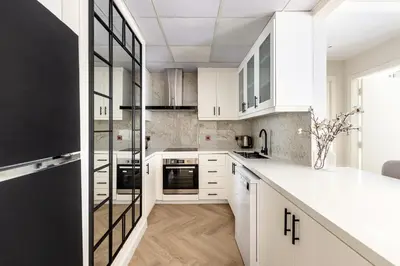 a white kitchen with white cabinets and black appliances at Luxury 1 bedroom with beautiful marina view! in Dubai
