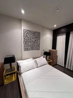 a bedroom with a large white bed and two tables at The Sand Castle - Ubora Residence Tower, Business Bay, Burj Khalifa View in Dubai
