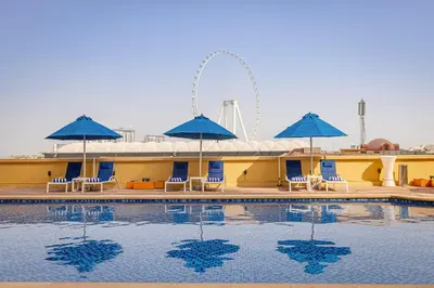 a swimming pool with blue umbrellas and chairs at Roda Amwaj Suites Jumeirah Beach Residence in Dubai