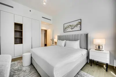 a white bedroom with a large white bed and a table at Amazing 1 bedroom in Port De La Mer near the sea in Dubai