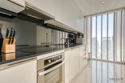 a kitchen with white cabinets and a large window at Overlooking Marina Views Next to Marina Mall 1BR Unit, The Address Residences, Dubai Marina by Deluxe Holiday Homes in Dubai