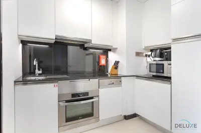 a kitchen with white cabinets and stainless steel appliances at Urban Studio at The Address Residences Dubai Marina by Deluxe Holiday Homes in Dubai