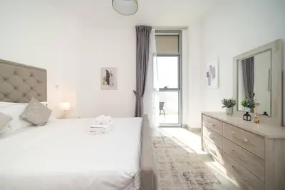 a white bedroom with a large bed and a window at StoneTree - Furnished 2BR with floor-to-ceiling window in Dubai