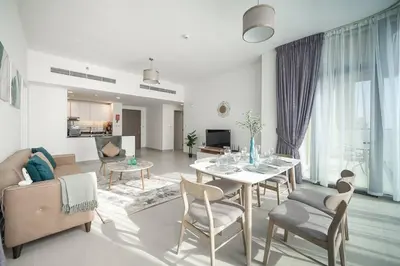 a living room with a couch and a table and chairs at StoneTree - Furnished 2BR with floor-to-ceiling window in Dubai