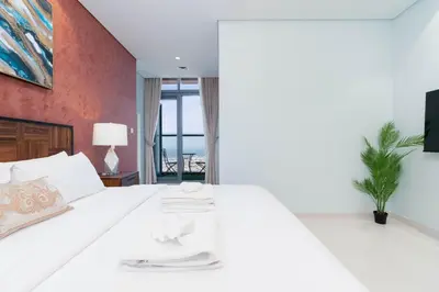 a bedroom with a white bed with a red wall at Lux BnB Paramount Midtown I Ocean View in Dubai