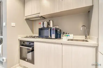 a kitchen with a sink and a microwave at Limited Time Offer Modern 1BR at DAMAC Zada Tower by Deluxe Holiday Homes in Dubai