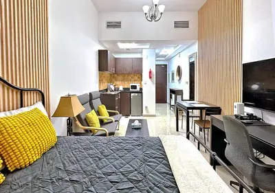 a room with a bed and a kitchen and a living room at Lovely Studio Apartment in Hanover Square, JVC in Dubai