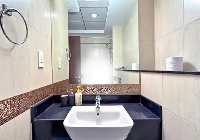 a bathroom with a white sink and a mirror at Lovely Studio Apartment in Hanover Square, JVC in Dubai