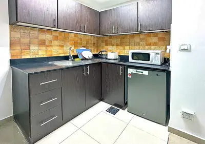 a small kitchen with a sink and a microwave at Lovely Studio Apartment in Hanover Square, JVC in Dubai
