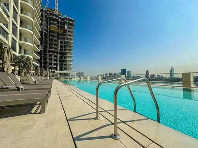 a swimming pool with chairs and a building at HiGuests - Emaar Beachfront Haven with Majestic Marina Views in Dubai