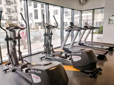 a row of treadmills in a gym with windows at Nasma Luxury Stays - Home-Style 2BR Apartment with a Balcony View in Dubai