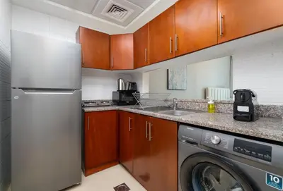 a kitchen with a refrigerator and a washing machine at Nasma Luxury Stays - Sophisticated Studio Apt with Stunning Marina View in Dubai