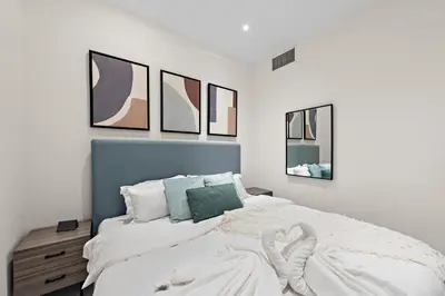 a bedroom with a white bed with four pictures on the wall at FIRST CLASS 2BR with Full Boulevard View in Dubai