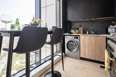 a kitchen with a table and a washing machine at Frank Porter - Regina Tower in Dubai