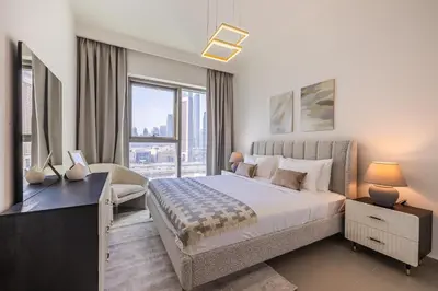a bedroom with a bed and a desk and a window at 3BDR with Maid Room I Downtown I Burj Khaliva View in Dubai
