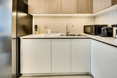 a kitchen with white cabinets and a sink at Pleasant 2BD new apartment in Dubai Creek Harbour in Dubai