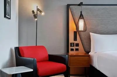a bedroom with a red chair next to a bed at The First Collection Waterfront, Dubai, a Tribute Portfolio Hotel in Dubai