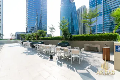 a row of tables and chairs on a patio with tall buildings at Arbab Homes Luxury 1BR- Canal View - Damac Zada Tower in Dubai