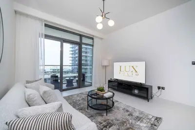 a white living room with a couch and a tv at Marina Vista 1 Bed with Private Beach and Gorgeous Skyline in Dubai