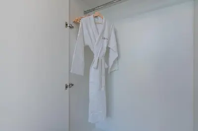 a white robe hanging on a rack in a room at Citihome - 1BR at Merano Tower by Damac in Dubai