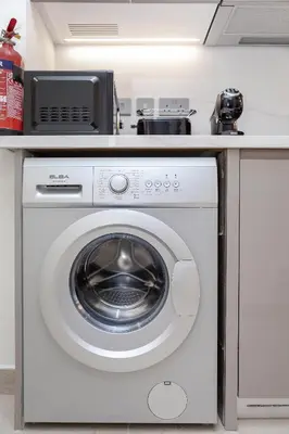 a white washing machine under a counter in a kitchen at Modern studio in Azizi Riviera in Dubai