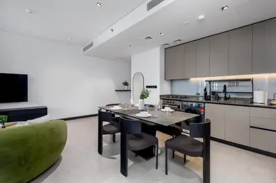 a kitchen with a table and a green couch at Waves Holiday Homes - 15 Northside, Tower 1, Two Bedroom in Dubai