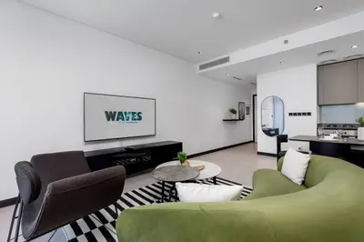 a living room with a green couch and chairs at Waves Holiday Homes - 15 Northside, Tower 1, Two Bedroom in Dubai