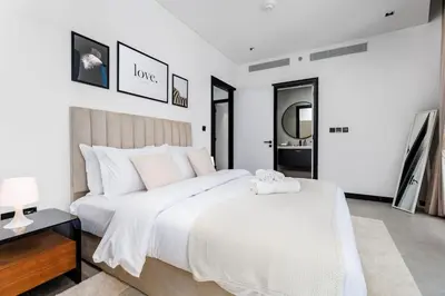 a white bedroom with a large bed and a mirror at Waves Holiday Homes - 15 Northside, Tower 1, Two Bedroom in Dubai
