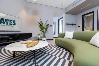 a living room with a green couch and a table at Waves Holiday Homes - 15 Northside, Tower 1, Two Bedroom in Dubai