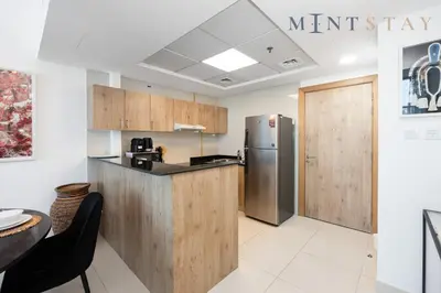 a kitchen with wooden cabinets and a refrigerator at Continental Tower, Dubai Marina - Mint Stay in Dubai
