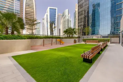 a park with benches and grass in a city at 1BR Zada Tower l Two Balconies & City Views in Dubai