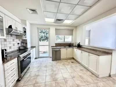 a large kitchen with white cabinets and a tile floor at Golf Facing 5Bedroom Villa in Novelia Village in Dubai