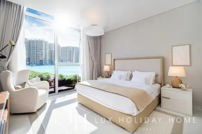 a bedroom with a bed and a large window at LUX The District One Lagoon View Suite in Dubai