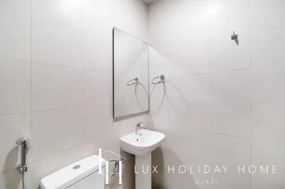 a white bathroom with a sink and a mirror at LUX The District One Lagoon View Suite in Dubai
