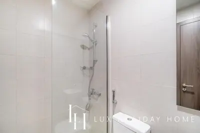 a bathroom with a shower with a toilet and a sink at LUX The District One Lagoon View Suite in Dubai