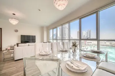 a dining room with a glass table and white chairs at Burj Residence 1, Downtown Dubai - Mint Stay in Dubai